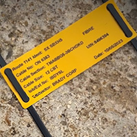 Una etiqueta sin adhesivo enrollada y fijada a una manguera.