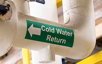 Una etiqueta en una tubería con la inscripción «Cold water return».