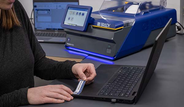 Un trabajador aplica una etiqueta de activos a un portátil.