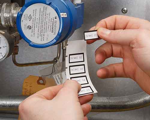 Una persona aplica etiquetas impresas con la M610 a una máquina.